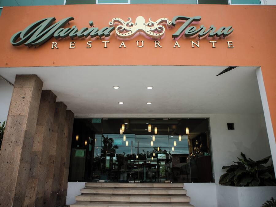 The exterior of Marina Terra Restaurante with a modern facade, large glass windows, and a staircase leading to the entrance.