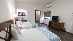 Ein Hotelzimmer mit zwei Betten, einem Fernseher, einer Holzkommode und einer Klimaanlage.
