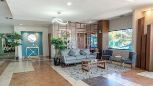 Eine moderne Lobby mit einer Couch, Sesseln, einem Couchtisch und einem dekorativen Raumteiler.