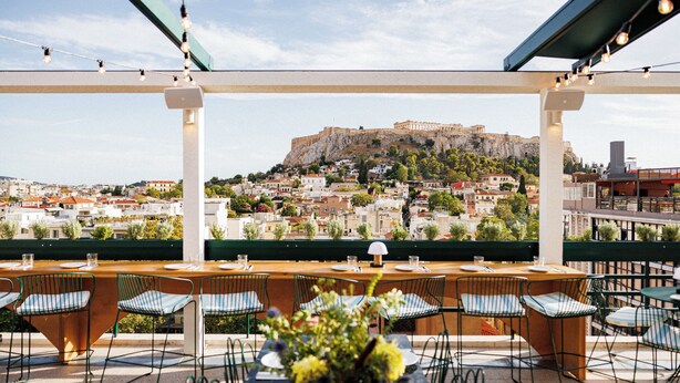 An outdoor dining area with a view of a historic hilltop fortress. - Regal Hotel Mitropoleos (Athens)