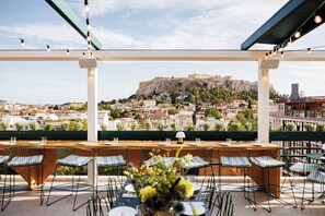 An outdoor dining area with a view of a historic hilltop fortress. - Regal Hotel Mitropoleos (Athens)