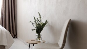 A modern room with a minimalist design, featuring a single chair, a small table, and a potted plant. - Regal Hotel Mitropoleos (Athens)