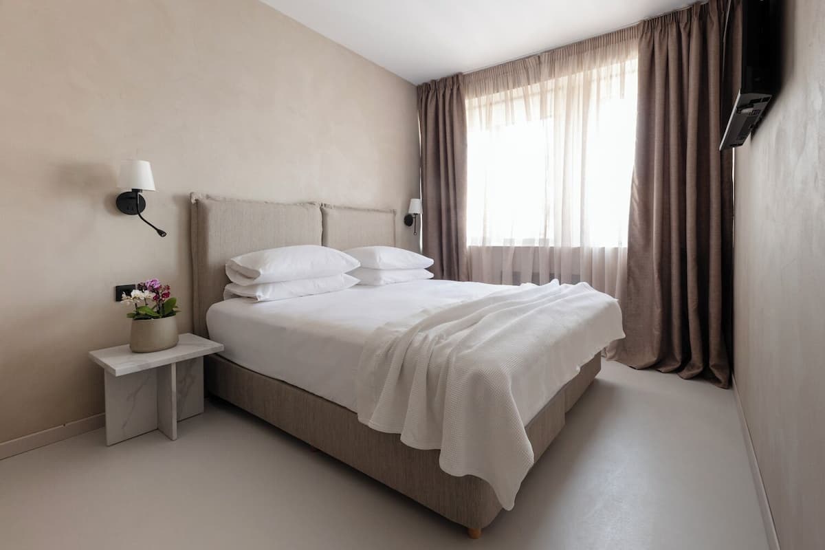 A modern bedroom with a bed, bedside tables, and a window with curtains.