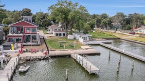 A waterfront property with a dock, a house with a deck, and a small boat. - Lakefront cottage on Muskegon Lake! Fire pit, 40' BOAT DOCK, near beach, shops (Muskegon)