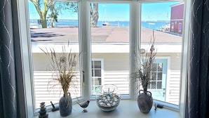 A bay window with a view of a beach and a building across the water. - Lakefront cottage on Muskegon Lake! Fire pit, 40' BOAT DOCK, near beach, shops (Muskegon)