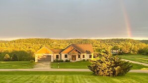 A two-story house with a garage, surrounded by a well-maintained lawn and trees. - 4 BR. Hot Tub. Pet Friendly. May Discounts! (Galena)