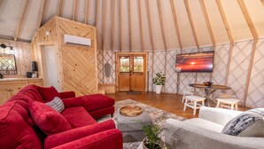 Ein gemütliches Zeltinneres mit einem roten Sofa, einem grauen Sofa und einem kleinen Tisch mit einer Pflanze.