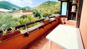 En balkon med udsigt over en bakke og bygninger.