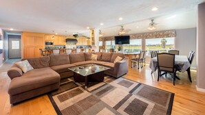 A spacious living area with a sectional sofa, a glass coffee table, and a dining area with a table and chairs. - Bring the whole family! 7 Bdrm, nice deck, big dock, close to fast water (Discovery Bay)