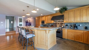 A modern kitchen with wooden cabinets, a central island with bar stools, stainless steel appliances, and pendant lighting. - Bring the whole family! 7 Bdrm, nice deck, big dock, close to fast water (Discovery Bay)