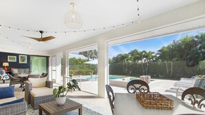A spacious living area with a view of a pool and tropical vegetation.