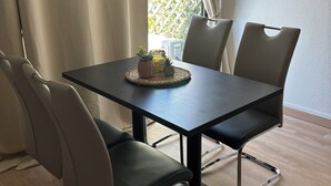 A dining area with a table, chairs, and an air conditioning unit. - Village Camarguais Logement 4 Personnes (Arles)