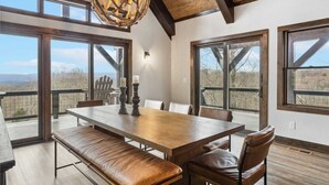 Un espace repas avec une grande table en bois, des bancs en cuir et un lustre de style rustique.