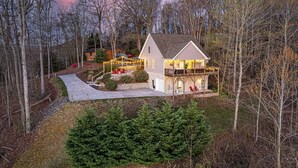 A two-story house with a balcony, surrounded by trees and a landscaped garden. - Mntn & Asheville Views! Movie Theater! Game Rm! Hot Tub! Fire Pit! Pets Welcome! (Candler)