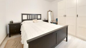 Un dormitorio con cama, mesita de noche, cómoda, espejo y armario.