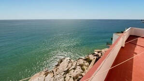 Vista costera con cielo despejado, costa rocosa y una edificación de techo rojo.