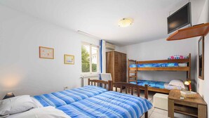 A bedroom with a bunk bed, a desk with a lamp, a television, and two framed pictures on the wall. - Holiday apartment Cheap accommodation in a great location (Bašanija)