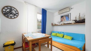 A room with a wooden table, blue sofa, and a wall clock. - Holiday apartment Cheap accommodation in a great location (Bašanija)