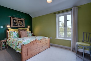 Une chambre à coucher avec un lit, une chaise, une fenêtre et un tableau accroché au mur.