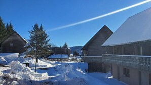A snow-covered building with a balcony, surrounded by snow and trees.