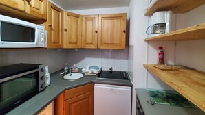 A compact kitchen with wooden cabinets, a microwave, a toaster, and a dishwasher.