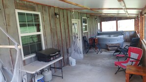 A rustic cabin interior with a hot tub, gas grill, and outdoor seating. - Falling Water Cabin (witts springs)