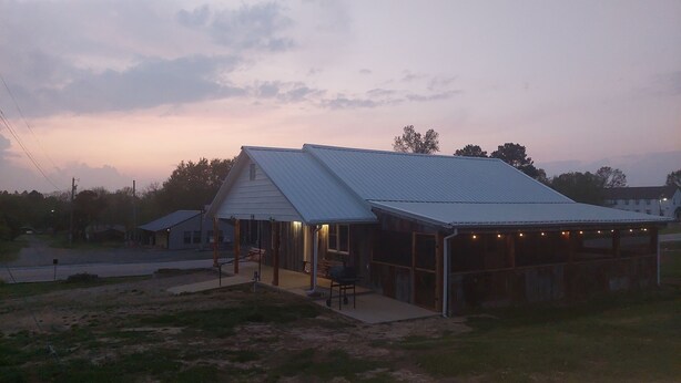 A two-story building with a metal roof and a covered porch area. - Falling Water Cabin (witts springs)