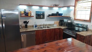 A kitchen with a stainless steel refrigerator, a dishwasher, a microwave, and a stove. There are wooden cabinets and a granite countertop. - Falling Water Cabin (witts springs)