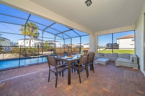 Un patio cubierto con piscina, mesa de comedor y zona de estar.