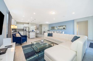Una sala moderna con un sofá, una mesa de centro de vidrio y una silla azul.