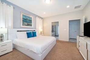 Ein Schlafzimmer mit Bett, Nachttischen, einem Fernseher und einem durchgehenden Türspalt sichtbaren Badezimmer.