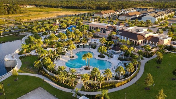 An aerial view of a resort with a central swimming pool, multiple buildings, and surrounding greenery. - Relax in Style: Private Pool, Wave Surfing & More! (Kissimmee)