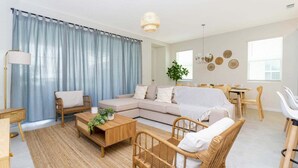 A living room with a sofa, coffee table, chairs, a dining table, and a lamp. - Relax in Style: Private Pool, Wave Surfing & More! (Kissimmee)