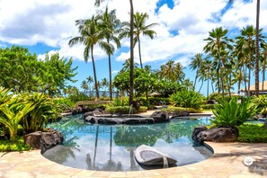 Ein Hotelpool, umgeben von Palmen und tropischer Vegetation.