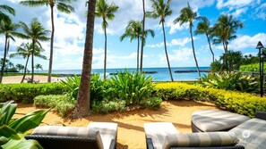Relax on the beach with ocean views, lounge chairs, and lush greenery.