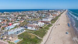 Luftaufnahme einer Küstenstadt mit Strand, Gebäuden und blauem Himmel.