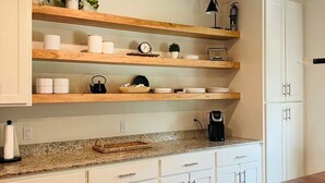 Eine Küche mit Holzböden, weißen Schränken und einer Arbeitsplatte aus Granit.
