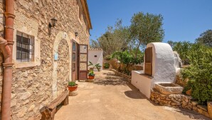 A narrow stone pathway leading to a rustic building with a white door and a large white wall feature. - Nice home in Felanitx (Felanitx)