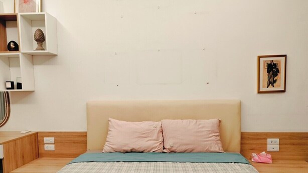 A neatly arranged bedroom with a bed, bedside tables, and a wall-mounted shelf with decorative items.