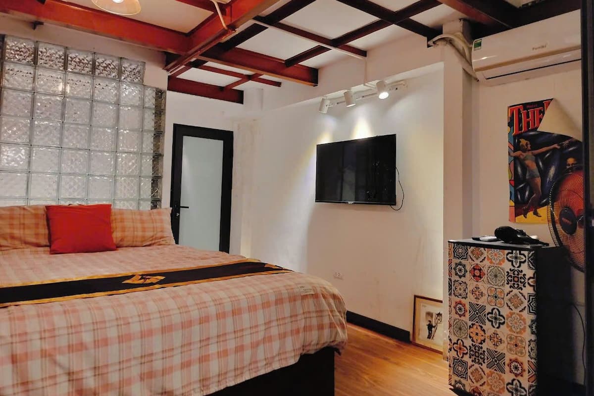 A bedroom with a bed, a TV, and a decorative cabinet.