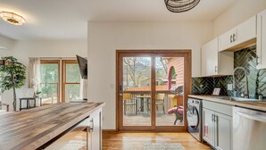 Una cocina moderna con encimera de madera, electrodomésticos de acero inoxidable y puerta corrediza de vidrio que da a un patio exterior.