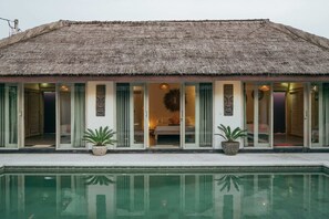 A thatched-roof building with a pool in front.