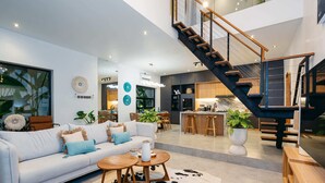 Een moderne woonkamer met een bank, salontafel en een trap naar een hoger niveau.