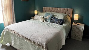 Ein ordentlich bezogenes Bett mit einer gebügelten Kopfteil, zwei Nachttische mit Lampen und ein gerahmtes Bild an der Wand.