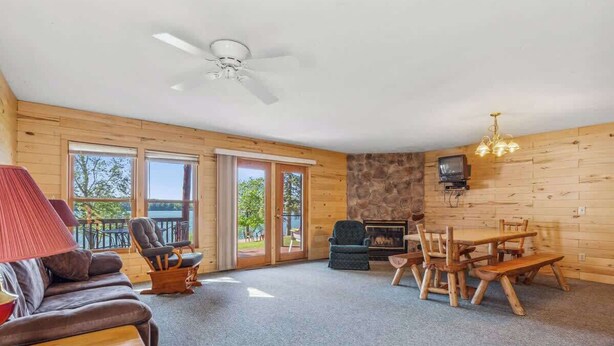 L’intérieur chaleureux d’un chalet comprend un canapé, une table à manger, des chaises, une cheminée et un téléviseur.