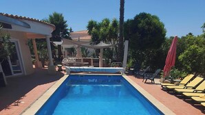 A rectangular swimming pool with a tiled edge, surrounded by a patio area with chairs and umbrellas. - ALGARVE ONE - Sports & Wellness Oasis, Volleyball, Billiards (Carvoeiro)