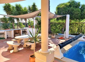 Ein Poolbereich mit Liege, Tisch und Grill.