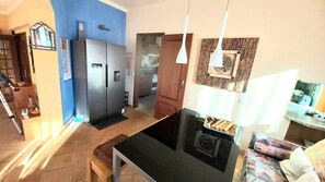 A modern kitchen with a refrigerator, a dining table, and a sofa. - ALGARVE ONE - Sports & Wellness Oasis, Volleyball, Billiards (Carvoeiro)
