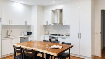 A modern kitchen with white cabinetry, a wooden dining table, and black chairs.