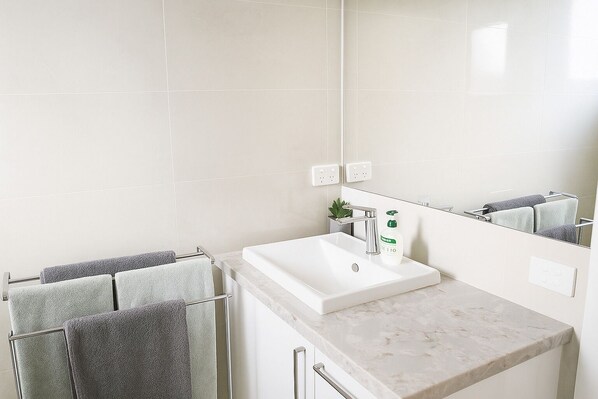 A bathroom with a white sink, a mirror, and towels on a rack.